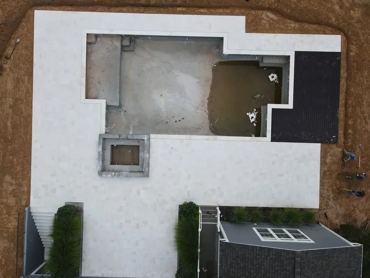 Aerial view of an unfinished swimming pool and spa with construction areas around it