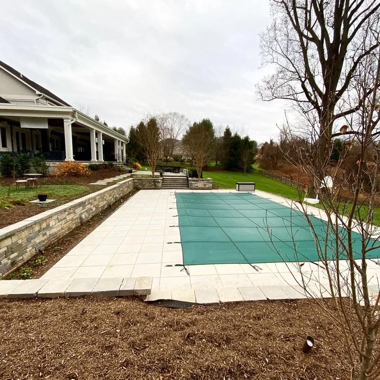Pool installation in progress beside a house with unfinished surroundings