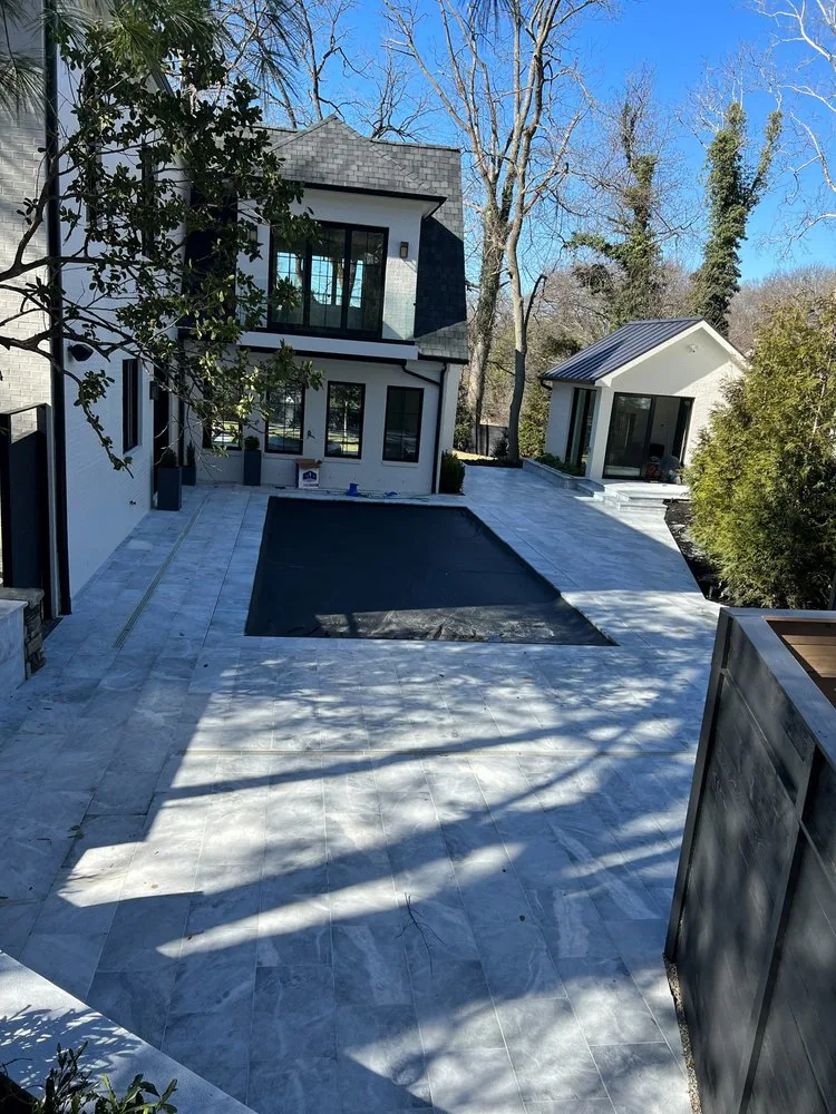 Stone pool terrace stretching alongside a modern home