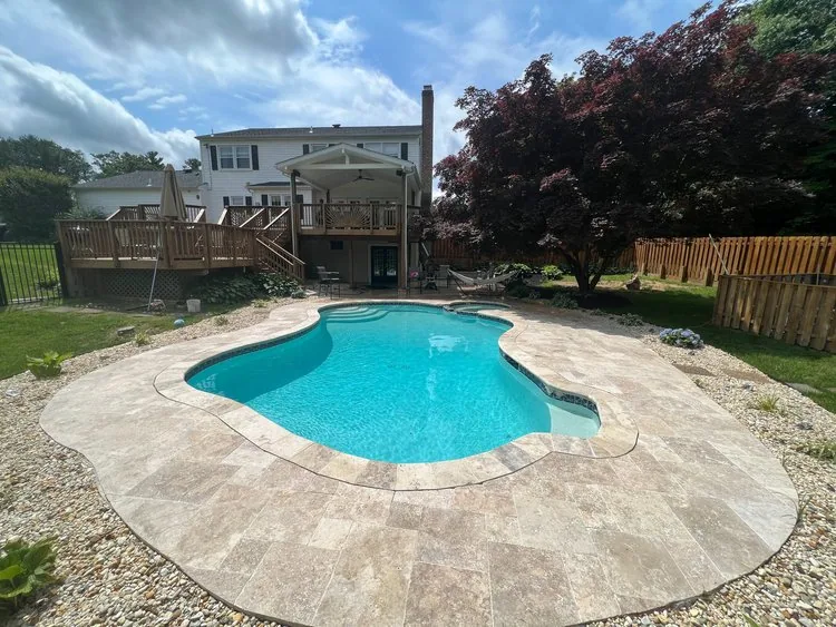 Curved turquoise pool with a natural stone surround in a residential backyard