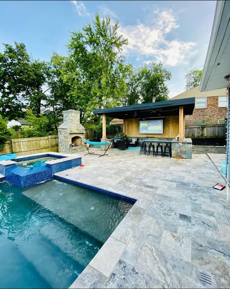 Pool and spa with a gray stone patio and a covered outdoor living area