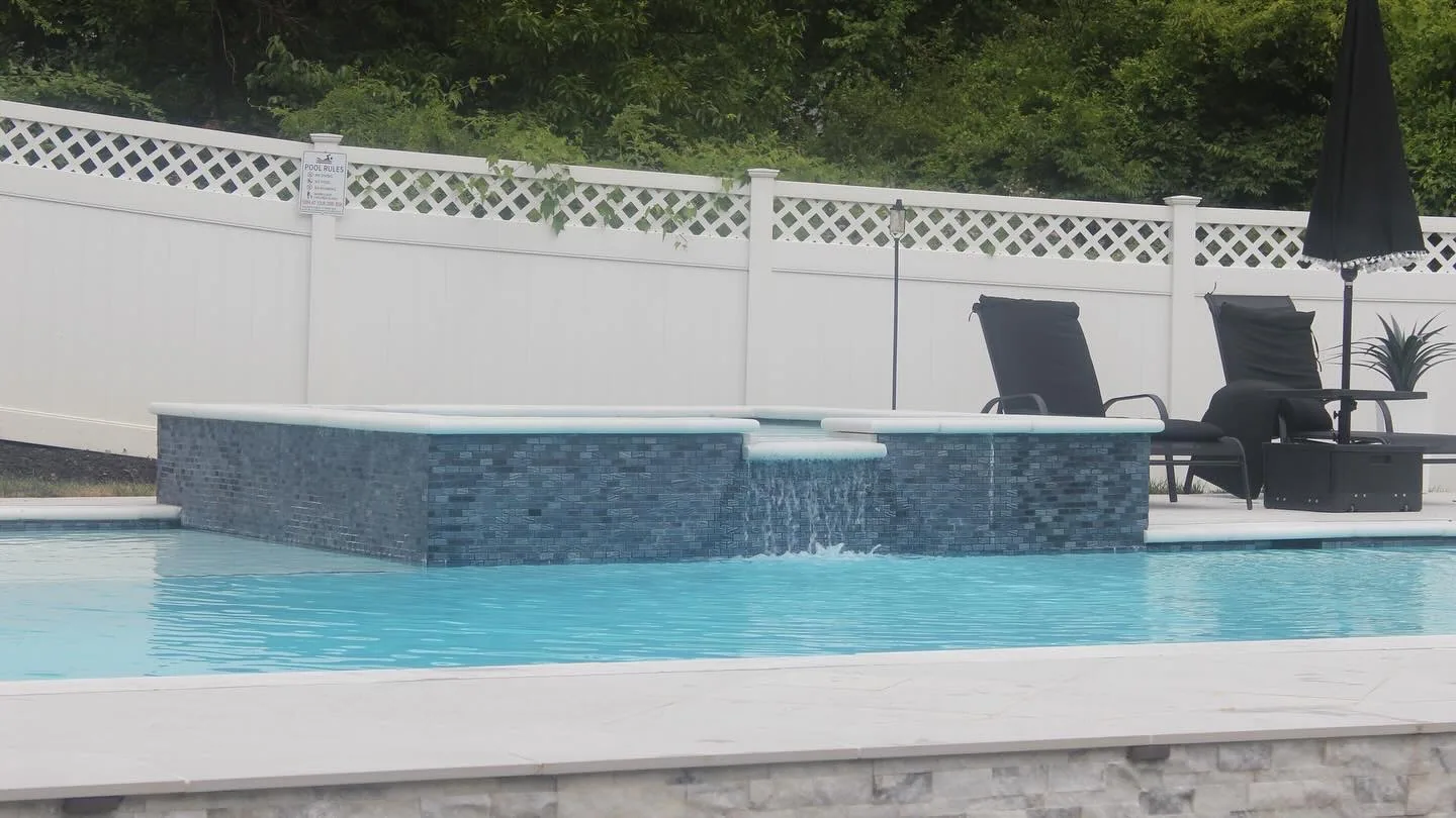 Raised tiled spa with water flowing into a rectangular swimming pool